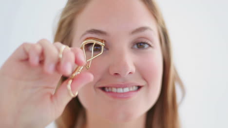 Mujer-Sonriente-Usando-Un-Rizador-Para-Sus-Pestañas