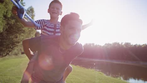 Tracking-video-of-father-and-son-playing-with-a-plane