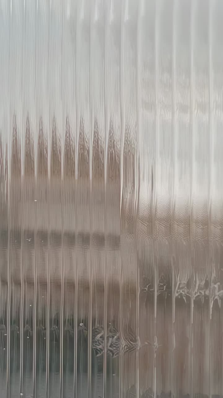 Vídeo vertical: celular fazendo um movimento panorâmico e capturando um painel canelado translúcido em uma sala, revelando um motivo em relevo
