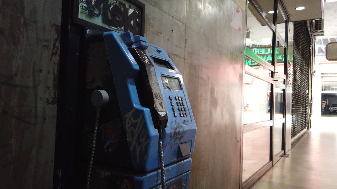 Closeup, vintage public phone, metallic obsolete retro machine inside 5th Avenue Gallery in Buenos Aires city, Argentina