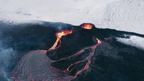 erupting volcano in remote iceland landscape with snowy mountains, aerial