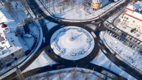 4k aerial view of roundabout road with circular cars in snow covered small european city at winter day, speed up