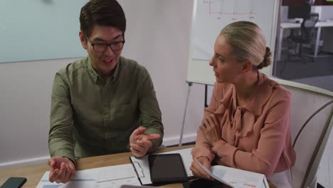 diverse male and female business colleagues in discussion in meeting room analyzing documents