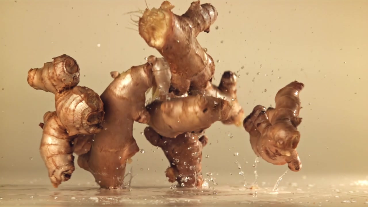 Fresh Ginger Roots Falling and Splashing in Water in Slow Motion
