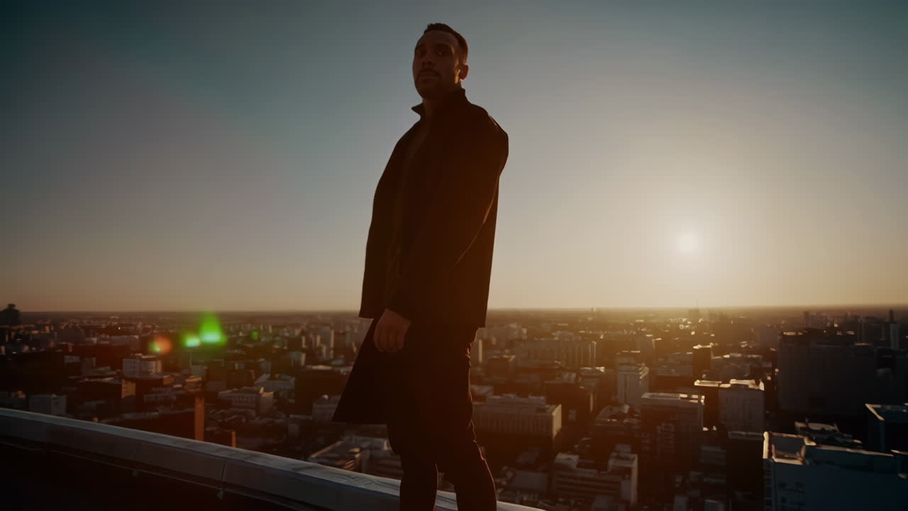 A man in silhouette on a city rooftop at sunrise or sunset