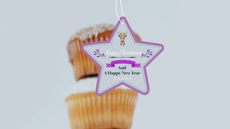 animation of christmas greetings on tag over cupcakes on white background