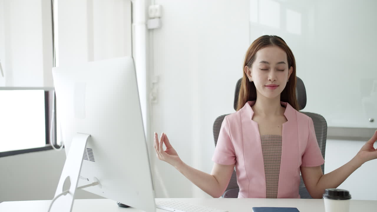 Woman meditating at her desk in the office