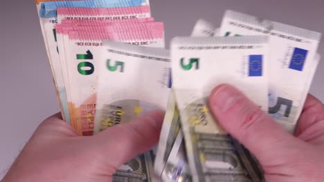 numerous 10, 20 and 50 euro notes counted by male hands on the table.