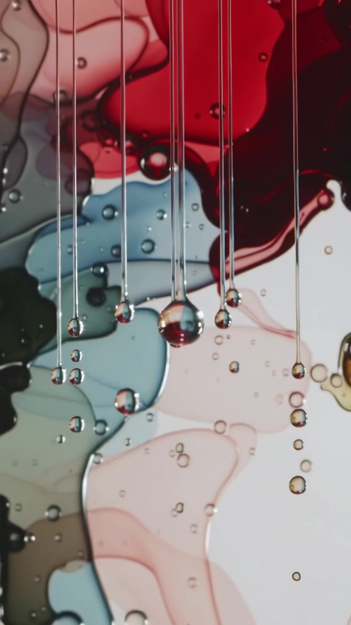 Video vertical: Gotas espesas cayendo de hilos por la gravedad en un estudio macro, con pequeñas burbujas.