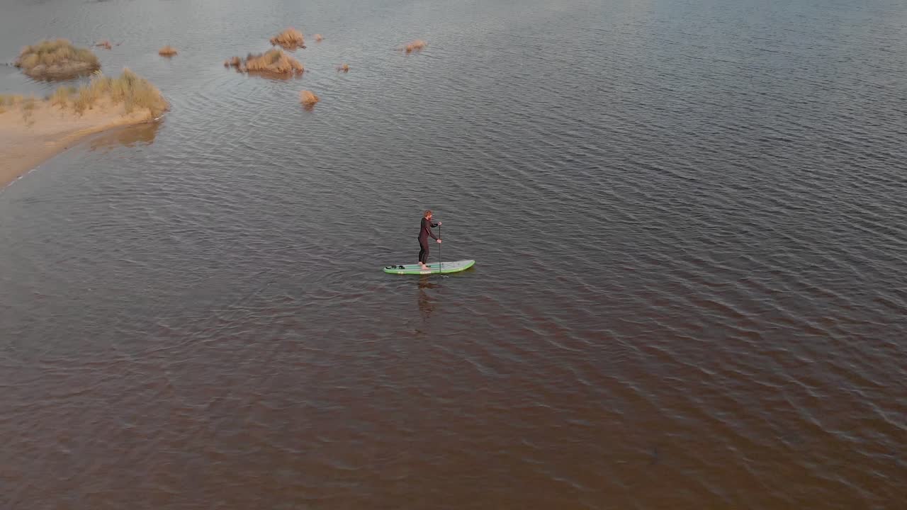 vista aérea de pájaro de un hombre en una tabla de remo en el estuario de un lago a lo largo de la costa de australia
