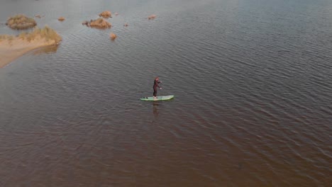 Vista-Aérea-De-Pájaro-De-Un-Hombre-En-Una-Tabla-De-Remo-En-El-Estuario-De-Un-Lago-A-Lo-Largo-De-La-Costa-De-Australia