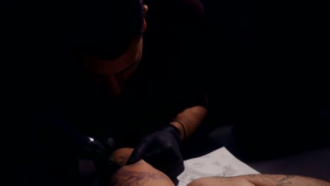artista del tatuaje haciendo tatuaje con máquina de tatuaje y tinta