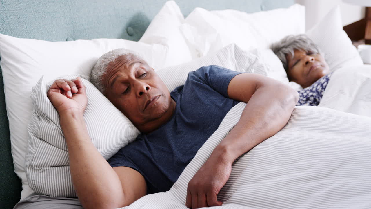un anciano preocupado se despierta al lado de su esposa por la mañana.