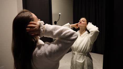 Attractive-young-Caucasian-woman-tying-her-hair-with-a-scrunchie-alone-while-looking-at-the-mirror-reflection