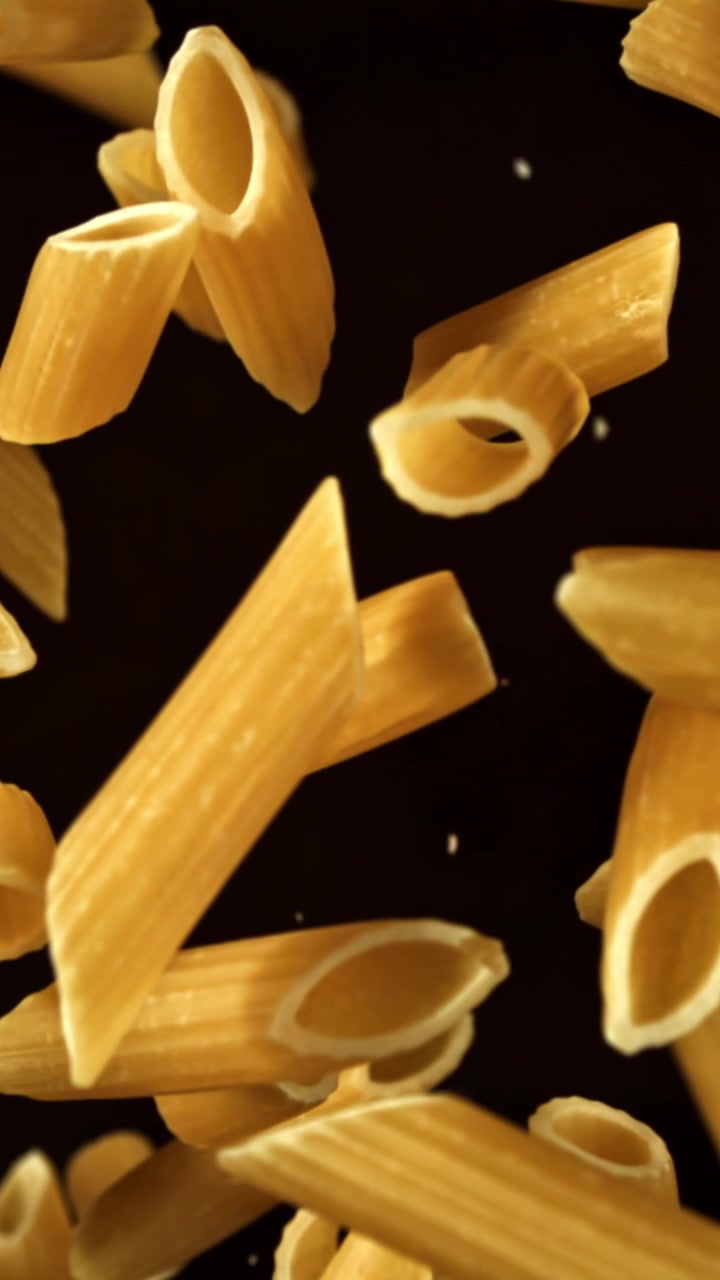 Penne dorate in caduta al rallentatore su sfondo nero