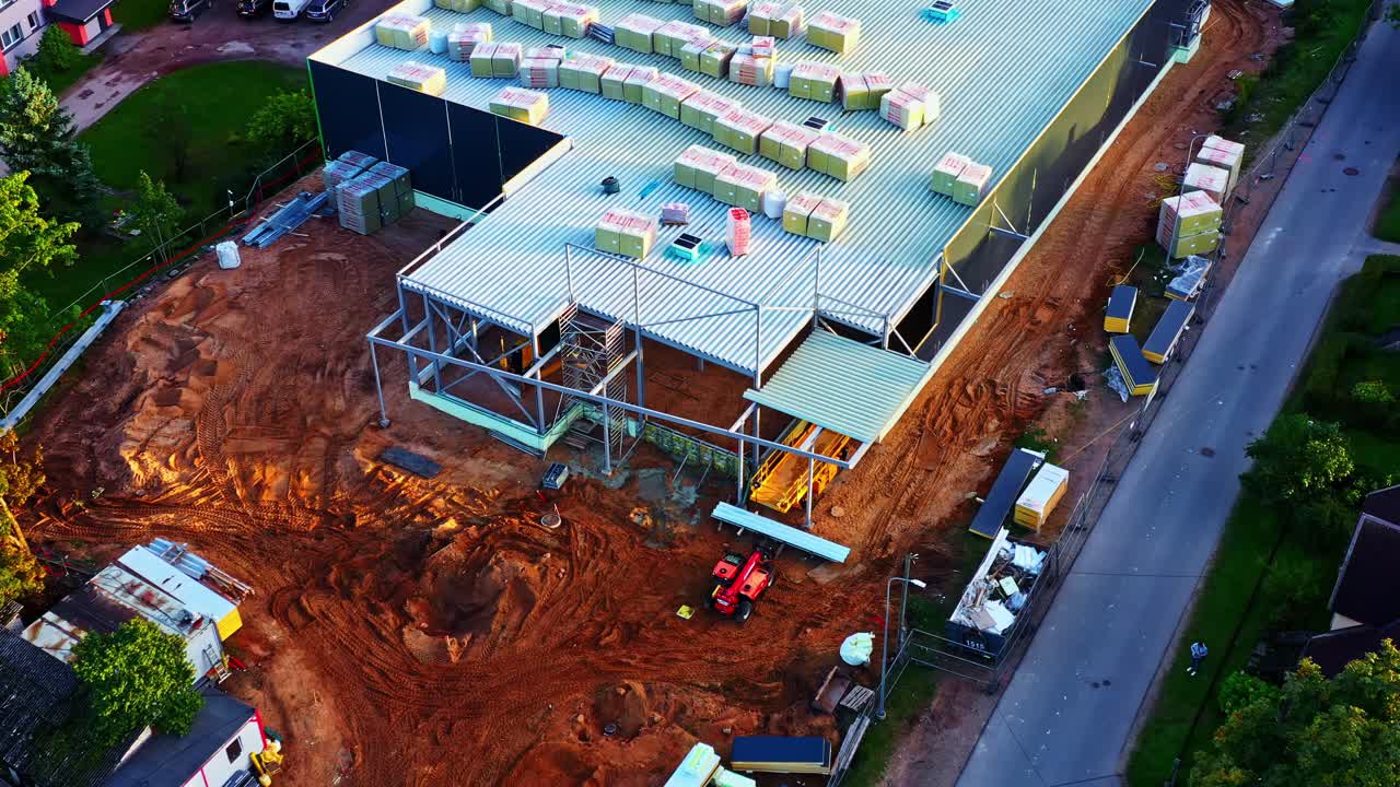Large commercial building under construction viewed from above with materials on roof