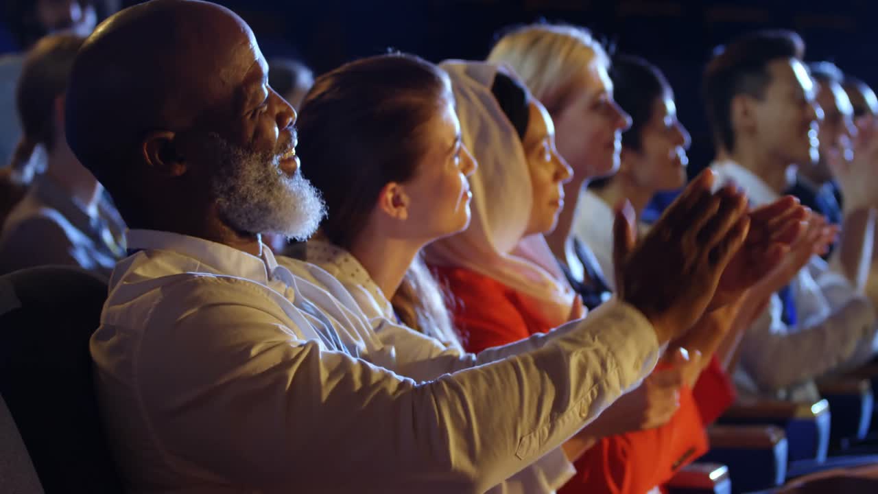 Business people applauding while sitting on seats in auditorium 4k