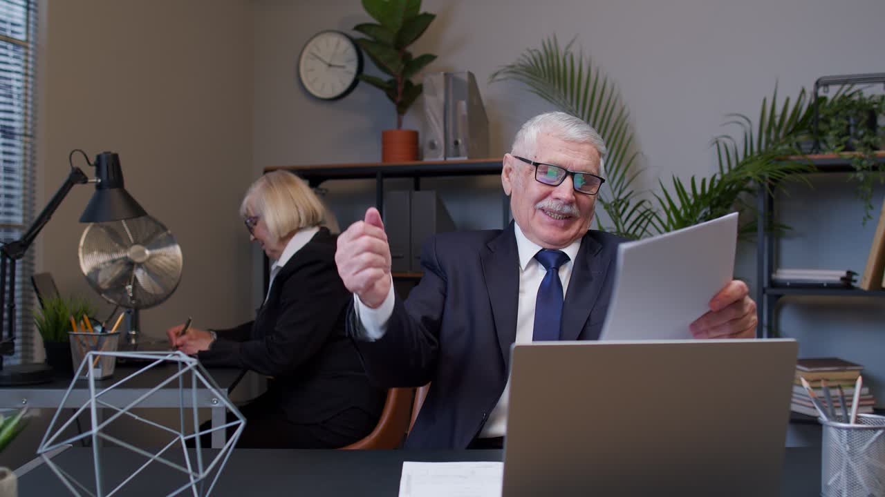 пожилой человек чувствует себя счастливым и счастливым достичь цели во время чтения документов, финансовых бумаг в офисе