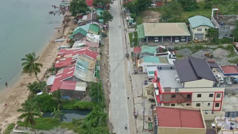 drone shot of the shoreline, people fishing at seashore, swimming and washing their fishing net