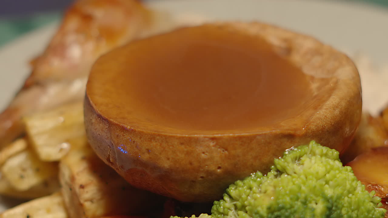 Static Shot of Whole British Traditional Festive Roast Chicken Dinner Plate with Yorkshire Pudding Full of Gravy. British Cuisine Eaten at Sunday Lunch