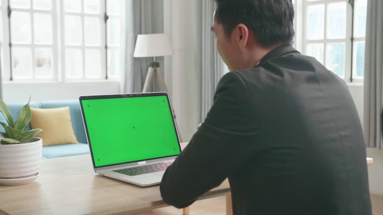 Asian Businessman Wearing Business Suit Talking On Green Screen Computer While Working At Home.