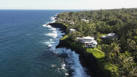 ocean waves crash into low cliffs below beautiful homes on hawaii