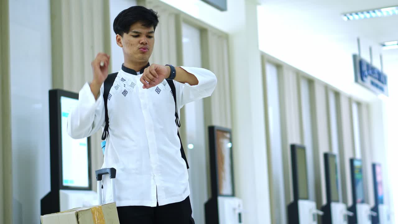 Worried young man looking at watch and afraid of being late on his schedule at terminal