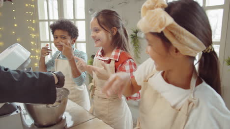 niños jugando con harina y chef haciendo masa en la clase magistral de cocina