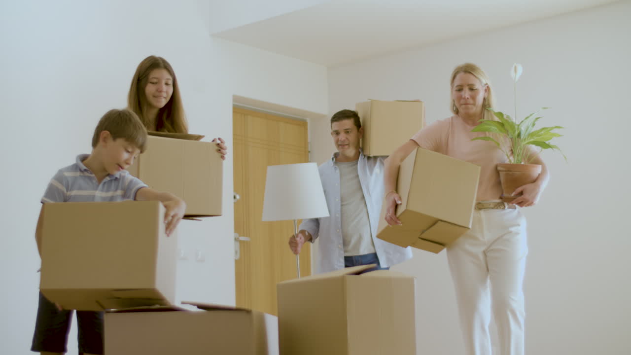 familia alegre entrando en un nuevo apartamento con cajas de cartón