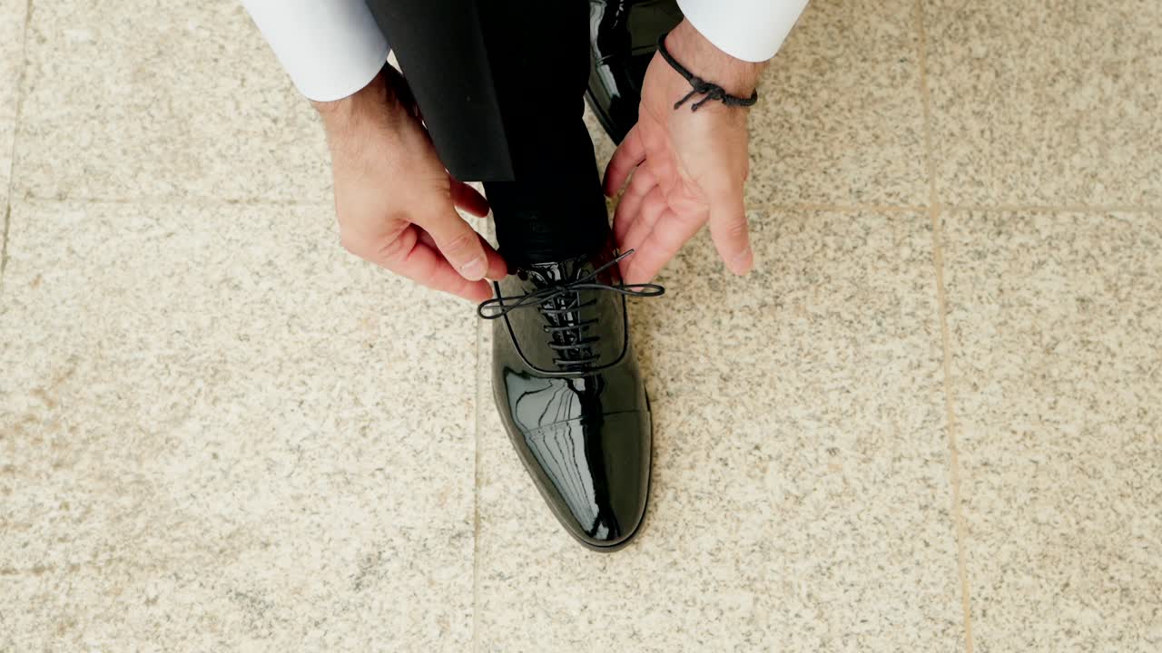 close up of man lacing formal shoe on textured balcony floor