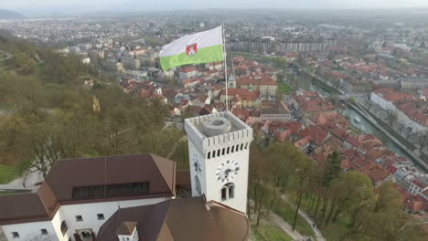 Fly-over-Ljubljana-castle-and-flag,-one-of-the-most-important-landmarks-of-the-city,-Slovenia