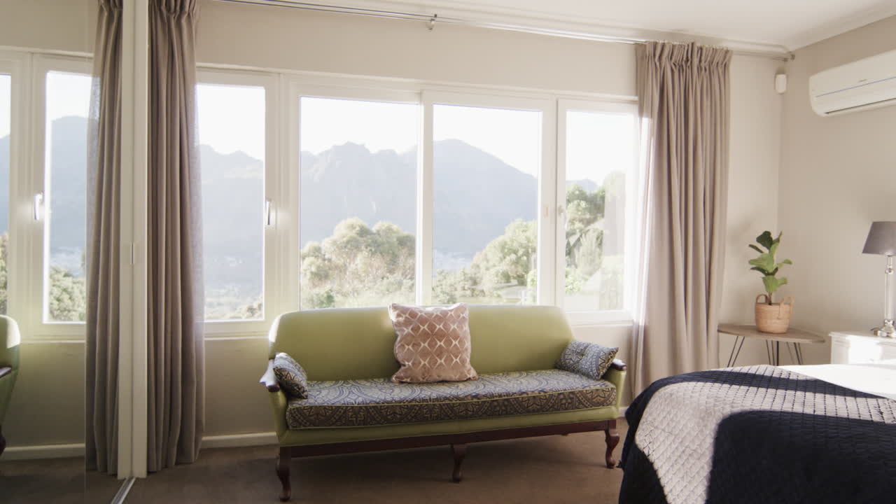 fotografía panorámica de un dormitorio soleado en el interior de la casa con vistas a la ladera de la montaña, en cámara lenta