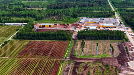 peat processing plant with yellow industrial buildings and large extraction field in foreground