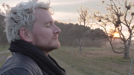 close up of a man in nature at sunset taking a deep breath