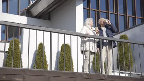 senior couple drinking coffee to go on a terrace in the park on a winter day