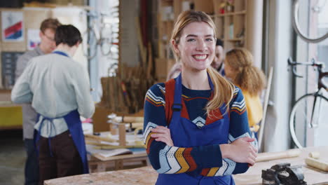 Portrait-Of-Female-Small-Business-Owner-In-Workshop-Assembling-Hand-Built-Bamboo-Bicycles