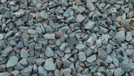 close up of some granite rocks that are blue, gray and red on the side of some railroad tracks during summer time in a cloudy day