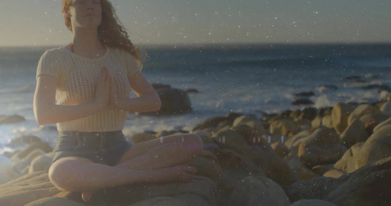 Telecamera che si allontana, donna seduta sulle rocce che preme i palmi delle mani mentre particelle tracciano le mani per la salute.