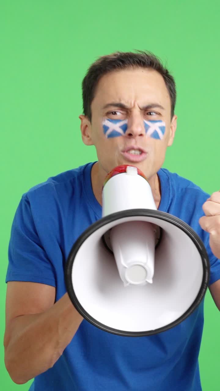 Excited man with scottish flag on face using a megaphone