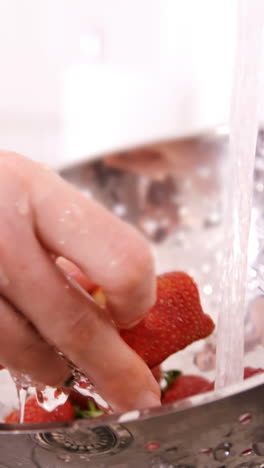 una mujer lavando fresas.
