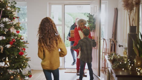 excited grandchildren greeting grandparents with presents visiting on christmas day