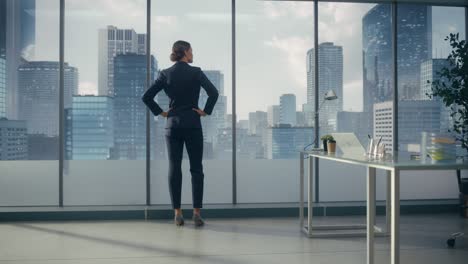 successful businesswoman in stylish suit looking out of the window at big city in downtown area. confident female ceo working on investment opportunity. real estate agent planning a development deal.