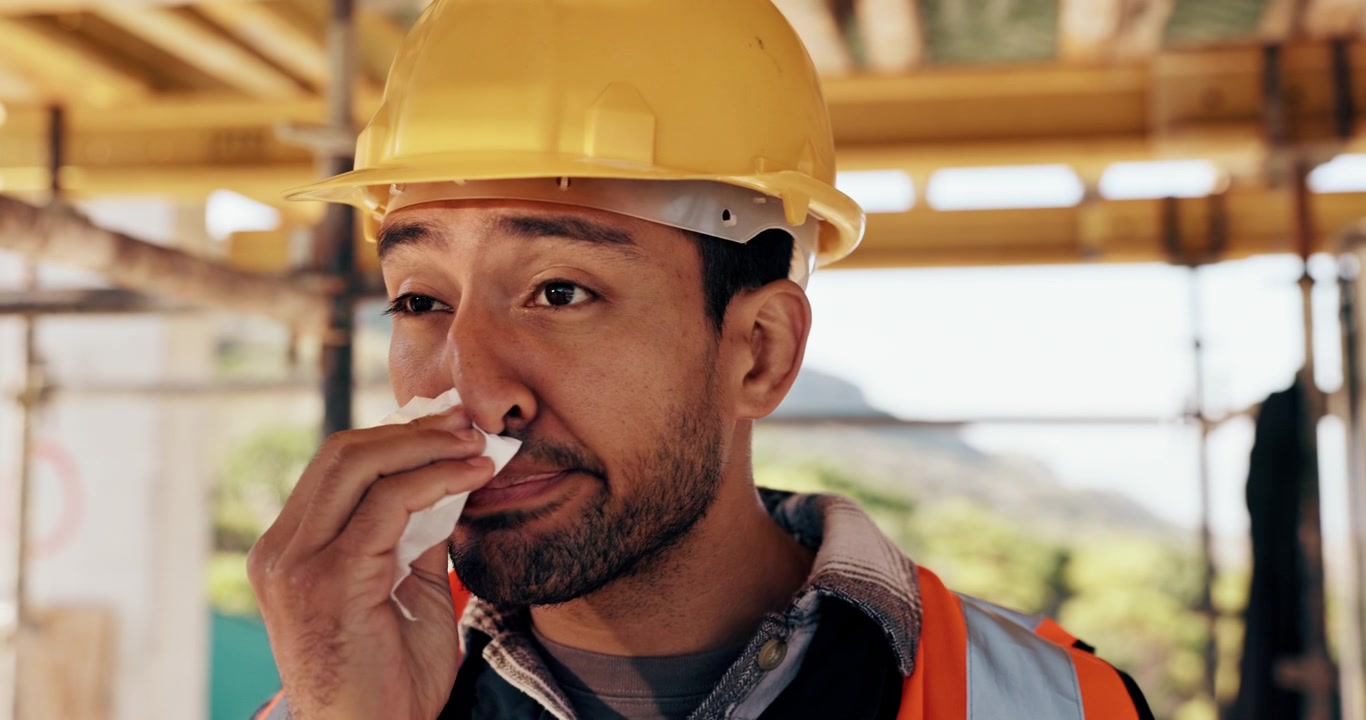Construction Worker Blowing Nose into Tissue on Site