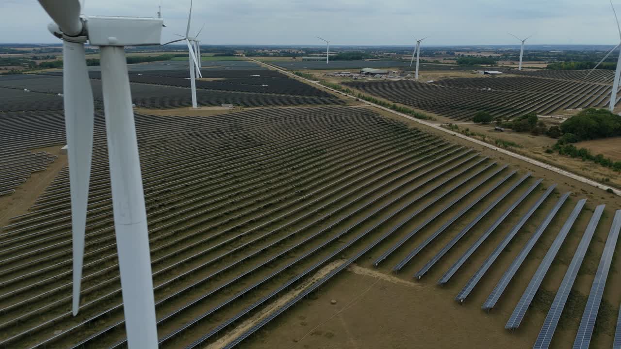 Drone footage showing solar fields and wind turbines producing renewable electricity in expansive countryside Raunds England UK