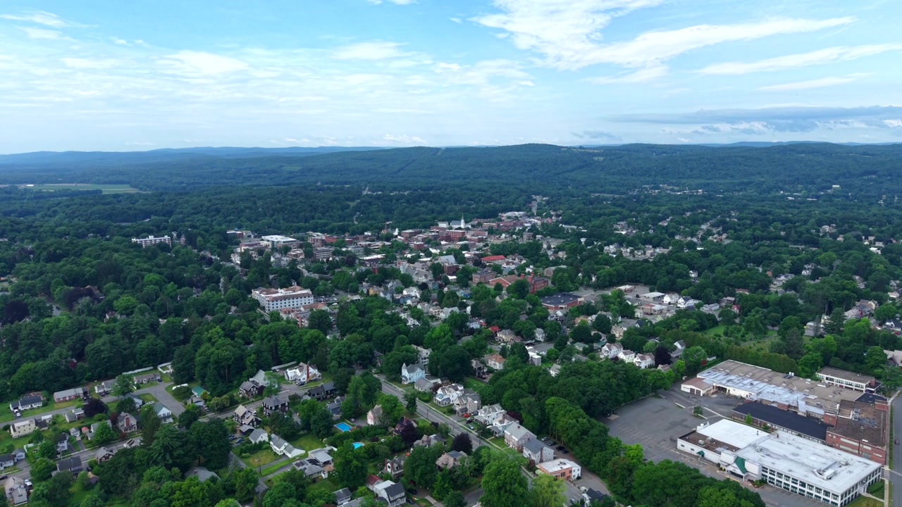 ABD, Massachusetts'te uzaktaki yeşil tepelerle çevrili Greenfield kasaba manzarası. Havadan yükselen çekim.