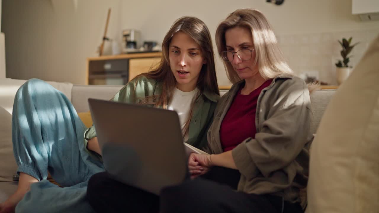 Mother and daughter using laptop together at home