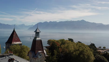 Aerial-of-clock-tower-overlooking-a-large-and-beautiful-lake-with-mountains-in-the-distance