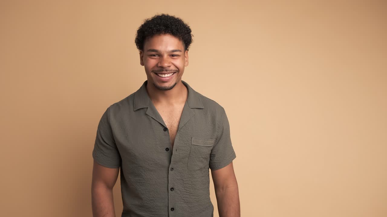 Cheerful man looking at camera in beige studio