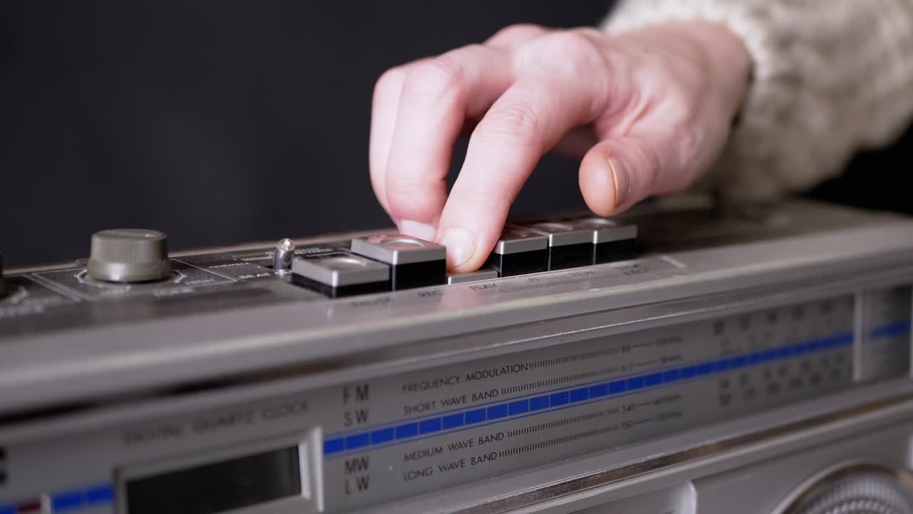 dedos femeninos presionando botones en una vieja grabadora de cinta vintage en una habitación oscura