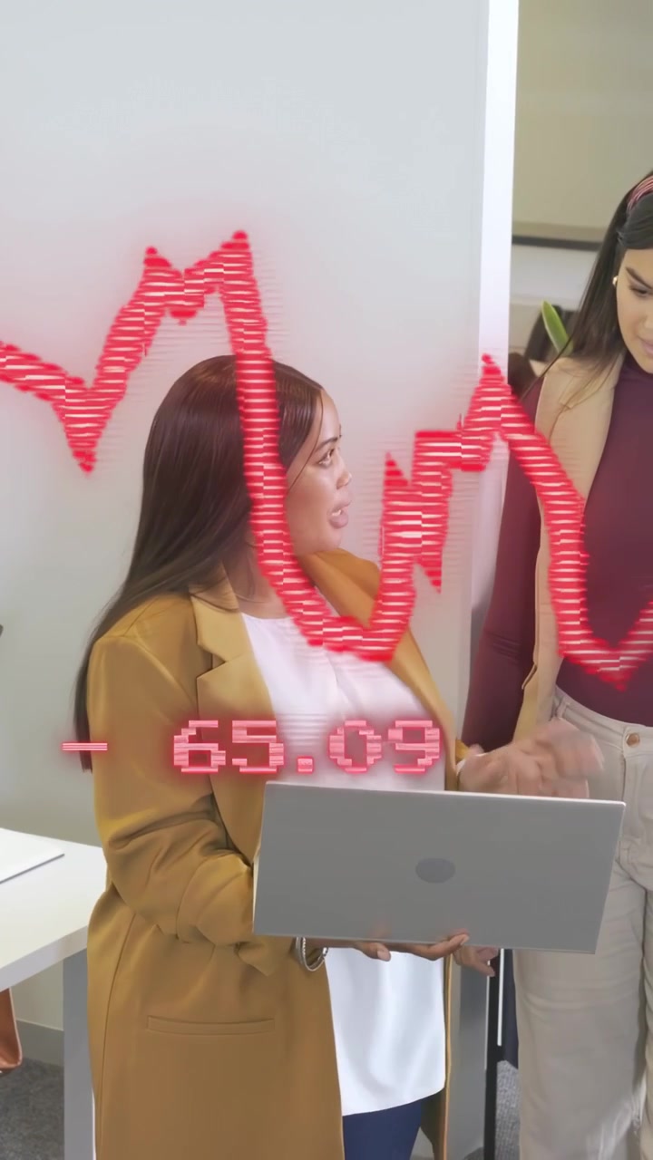 Video vertikal: Wanita memegang laptop di kantor, rekan kerja bergabung, meninjau overlay grafik keuangan.